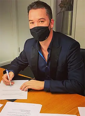Christian Panzeri an Tisch mit unterschriebenem Vertrag zur Eröffnung der Firma